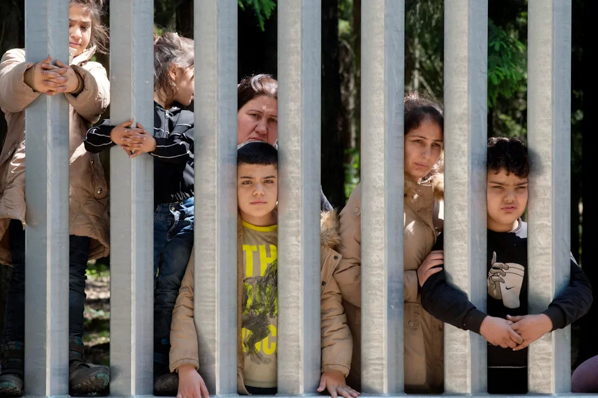 Migrant families trapped at Poland-Belarus border wall.
